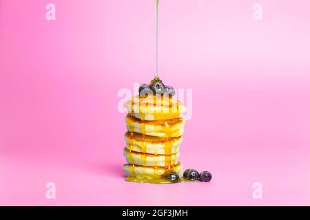 Pancakes with berries on a pink banner background. Lush delicious pancakes with blueberries and syrup for brunch on a minimal colored background. Beautiful bright food photo. High quality photo Stock Photo