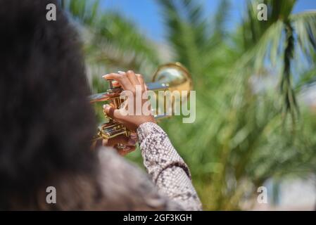 Rear close view of an african woman playing the trumpet in the city outside Stock Photo