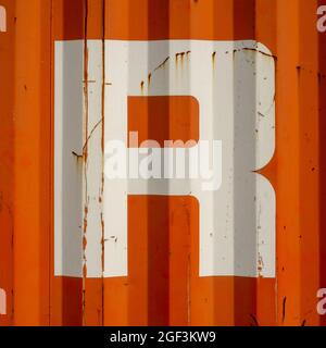 Grunge single letter R on an orange corrugated enameled metal background Stock Photo