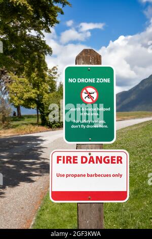 No drone zone signage and fire danger sign in public park. Flying drones is forbidden due to nearby local search and rescue helipad in North Vancouver Stock Photo