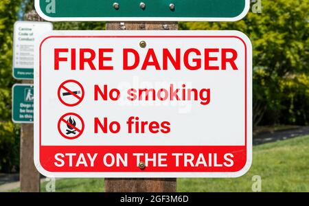 Fire danger sign, outside. Warning poster or information placard placed in parks, trails and nature during extreme heat or drought. No smoking and no Stock Photo