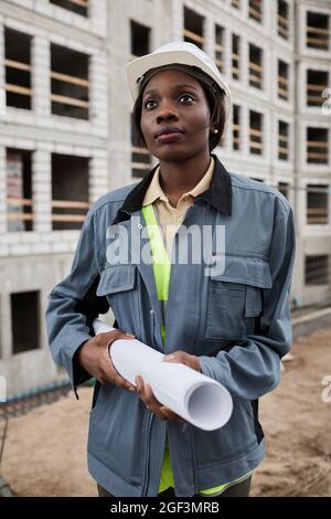 Vertical portrait of young female engineer posing at construction site Stock Photo