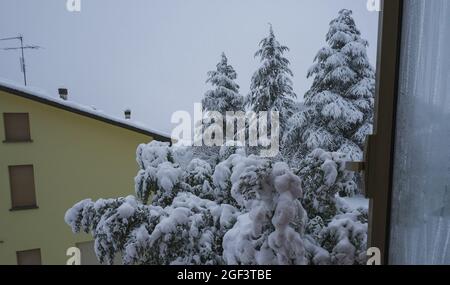 snow covered trees in winter, yellow house covered with snow through the window. Winter natural landscape Stock Photo