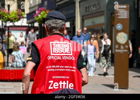 Bath, England - August 2021: Big Issue seller wearing an official vendor vest in a street in the city centre Stock Photo