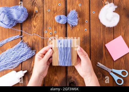 How to make a cute thread bird for decoration. Children's art project. DIY concept. Hands are made from blue threads of a blue dove. Step-by-step phot Stock Photo