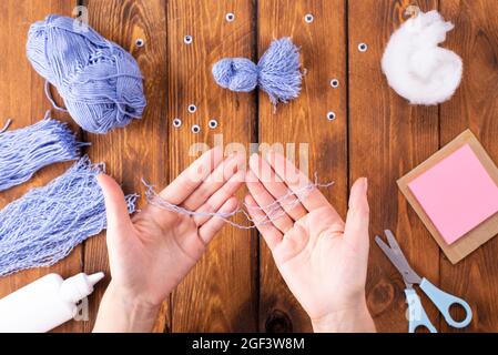 How to make a cute thread bird for decoration. Children's art project. DIY concept. Hands are made from blue threads of a blue dove. Step-by-step phot Stock Photo