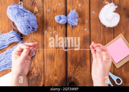 How to make a cute thread bird for decoration. Children's art project. DIY concept. Hands are made from blue threads of a blue dove. Step-by-step phot Stock Photo