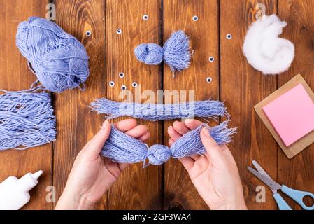 How to make a cute thread bird for decoration. Children's art project. DIY concept. Hands are made from blue threads of a blue dove. Step-by-step phot Stock Photo