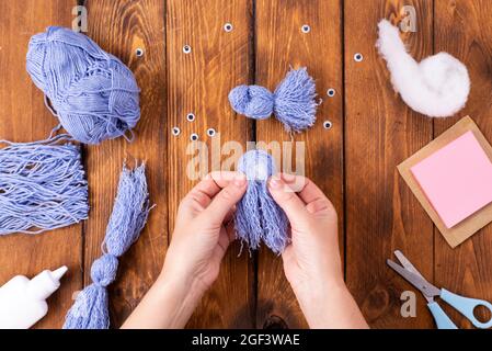 How to make a cute thread bird for decoration. Children's art project. DIY concept. Hands are made from blue threads of a blue dove. Step-by-step phot Stock Photo