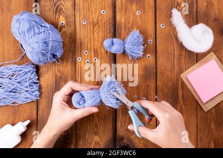 How to make a cute thread bird for decoration. Children's art project. DIY concept. Hands are made from blue threads of a blue dove. Step-by-step phot Stock Photo