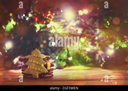 Sweet Xmas cookies and Christmas tree decorated with lights. Christmas background with freshly baked festive cookies Stock Photo