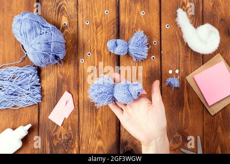 How to make a cute thread bird for decoration. Children's art project. DIY concept. Hands are made from blue threads of a blue dove. Step-by-step phot Stock Photo