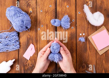 How to make a cute thread bird for decoration. Children's art project. DIY concept. Hands are made from blue threads of a blue dove. Step-by-step phot Stock Photo