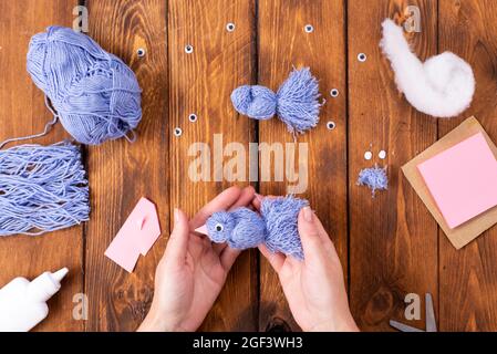 How to make a cute thread bird for decoration. Children's art project. DIY concept. Hands are made from blue threads of a blue dove. Step-by-step phot Stock Photo