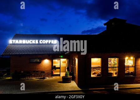 A night time shot  of a Starbucks Coffee, Drive Thru restaurant at Membury services on the M4 Motorway. The premises has an illuminated sign.