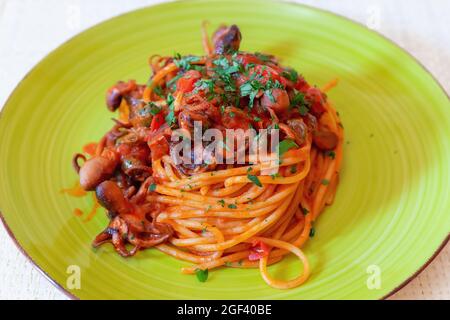 Spaghetti with octopus, tomato sauce, olives and capers. Typical recipe of Neapolitan cuisine, in Italy. Ready to eat Stock Photo