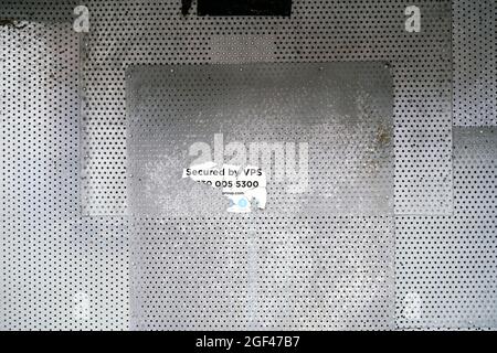 Torn sticker on perforated galvanised metal sheet Stock Photo