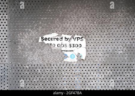 Torn sticker on perforated galvanised metal sheet Stock Photo