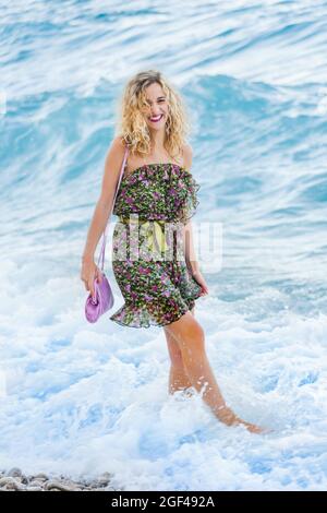 Teen girl is walking on a beach laughing looking at camera