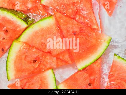 Melon close-up in liquid with bubbles. Slicec of red ripe melon in water. Close-up fresh slices of red melon on white background. Stock Photo