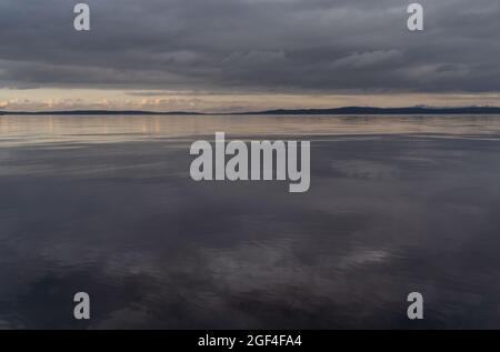 Beautiful autumn misty grey lake and cloudy sky reflection in the water at sunset. Dark and moody nature background. Great wallpaper design. Copy space. Stock Photo