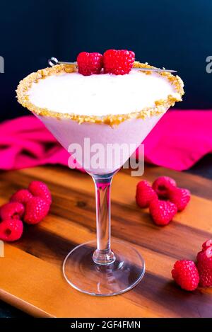 Raspberry Cheesecake Martini with a Berry Garnish: Raspberry cheesecake martini in a cocktail glass rimmed with graham cracker crumbs Stock Photo
