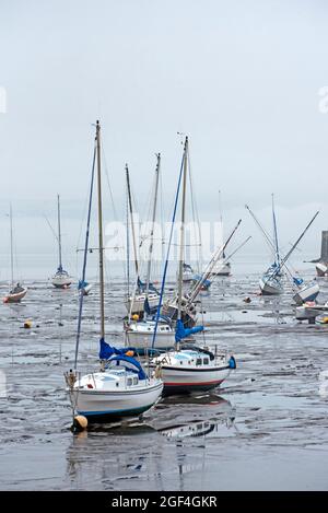 Small boats resting in the mud at low tide in Granton Harbour on the Firth of Forth, Edinburgh, Scotland, UK. Stock Photo