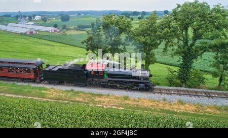 Aerial View of a Steam Locomotive Traveling Across a Fertile Farmland Landscape Blowing Smoke on a Beautiful Summer Day Stock Photo