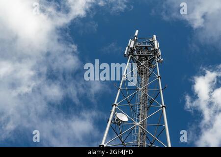 Bottom perspective pov of modern metal steel mobile 5g network wireless telecom tower against clear blue sky background on bright day. Microwave Stock Photo
