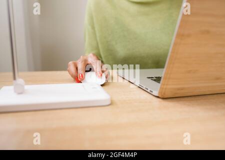 Woman using computer mouse while working on laptop Stock Photo