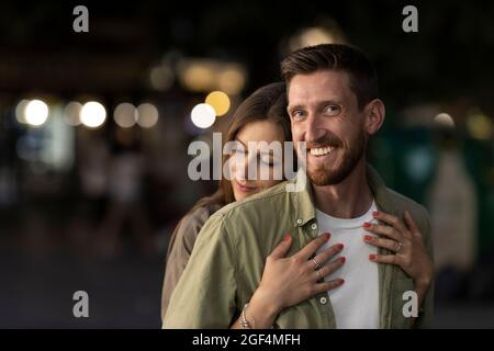 Woman embracing smiling boyfriend from behind Stock Photo