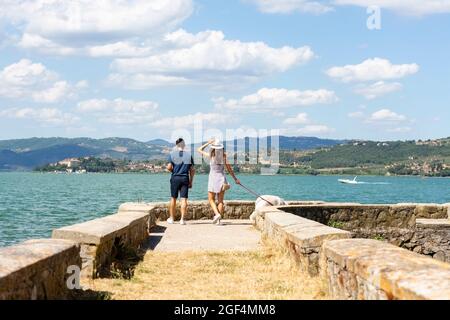 Tourist couple walking with dog on pier Stock Photo