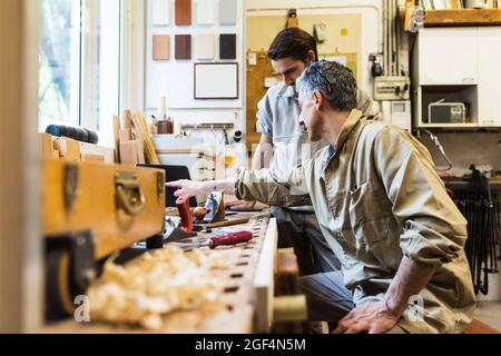 Mature carpenter discussing over laptop with male colleague at workshop Stock Photo