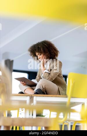 Woman with hand on chin using digital tablet at workplace Stock Photo