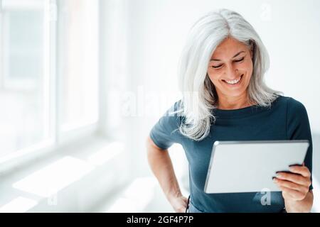 Smiling businesswoman using digital tablet at office Stock Photo
