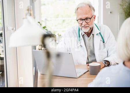 Male doctor using laptop at desk Stock Photo