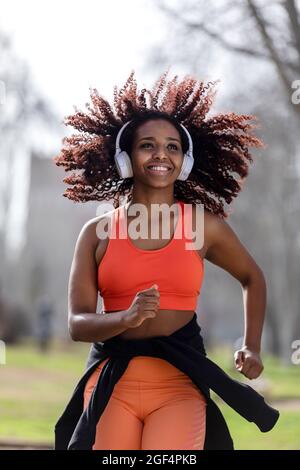 Happy female athlete with headphones running in park Stock Photo
