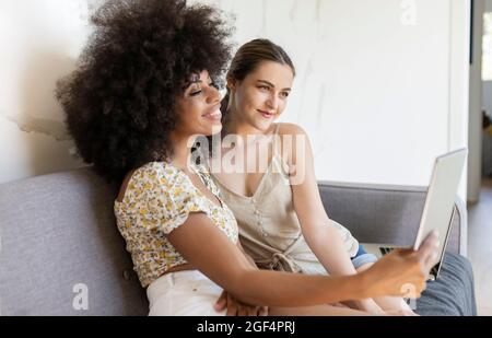 Smiling female friends using digital tablet at home Stock Photo