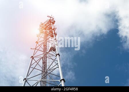 Bottom perspective pov of modern metal steel mobile 5g network wireless telecom tower against clear blue sky background on bright day. Microwave Stock Photo