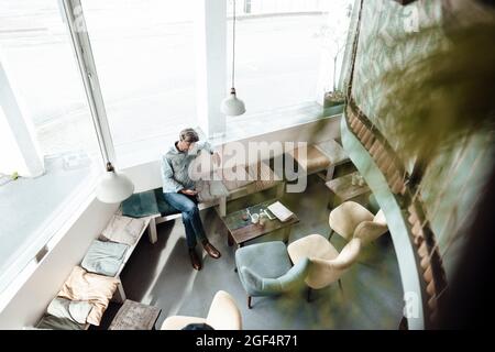 Mature man sitting by glass window in cafe Stock Photo