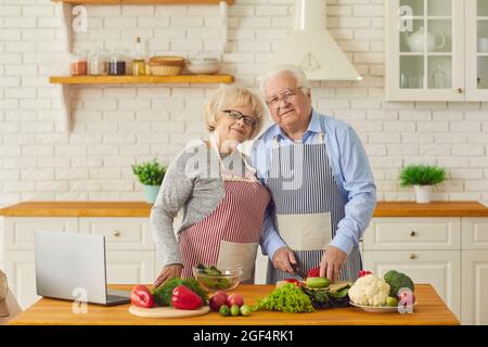 Portrait of a senior couple cooking healthy food at home with organic vegetables. Stock Photo