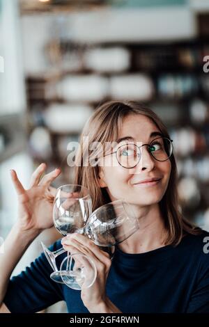 Young woman with brown hair holding wineglasses in cafe Stock Photo