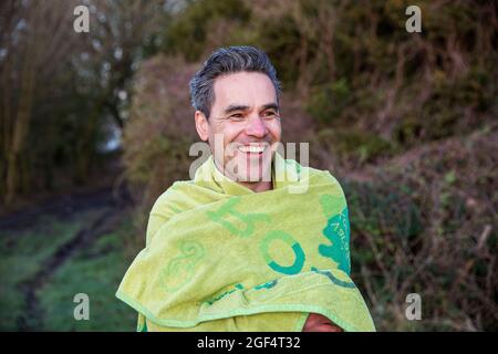 Smiling mature man wearing towel looking away Stock Photo