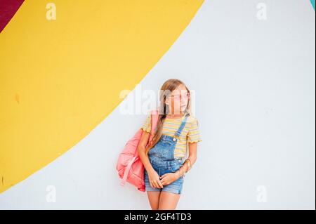 Boy with cap using mobile phone while standing in front of multi colored wall Stock Photo