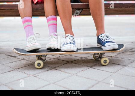 Friends using mobile phone while sitting on bench Stock Photo