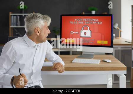 Man has computer security problems and receives a ransomware warning on the screen Stock Photo