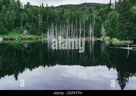Reflections on a cloudy day in the waters of the small Lac des Pères at the beginning of Pic de la Tête de Chien hiking trail in Monts Valin National Stock Photo