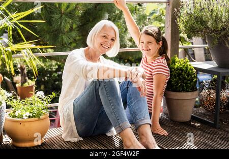 Smiling grandmother sitting with granddaughter at balcony Stock Photo