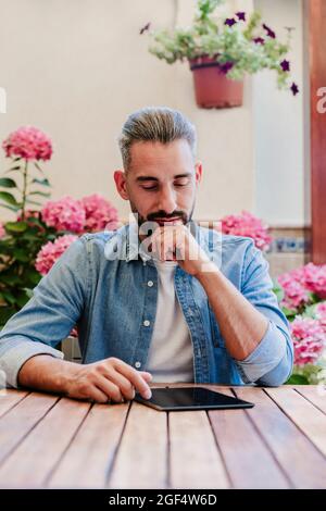 Male freelance worker using digital tablet at desk Stock Photo