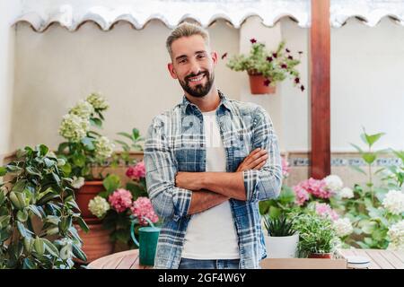 Handsome man with arms crossed standing at backyard Stock Photo